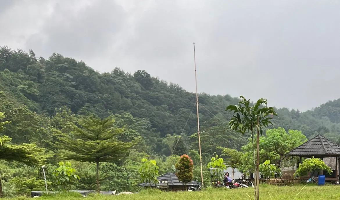 Area camping Sisi Cai dengan gazebo dan perbukitan hijau di belakangnya