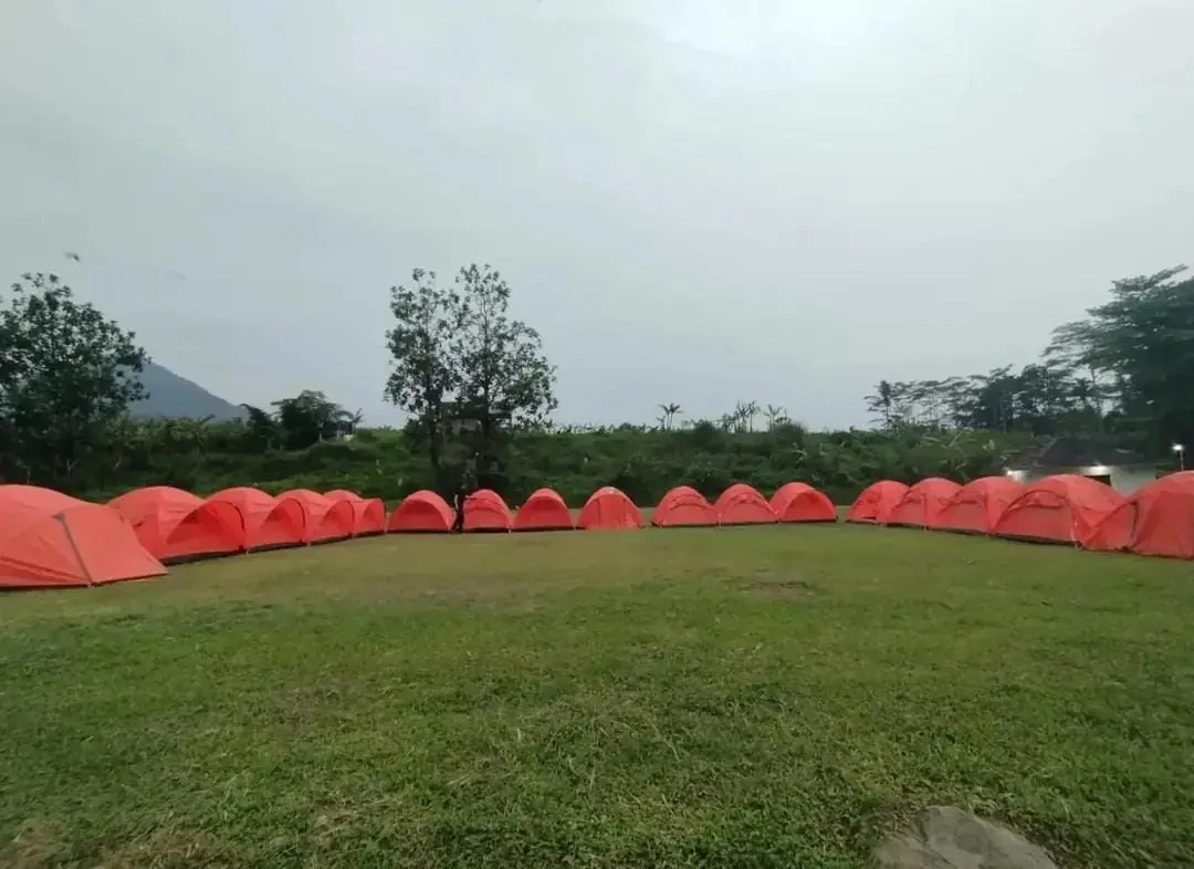 Deretan tenda dome oranye sewaan berdiri melingkari lapangan rumput Sisi Cai